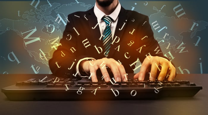 Young man in suit and formal clothing typing with letters around